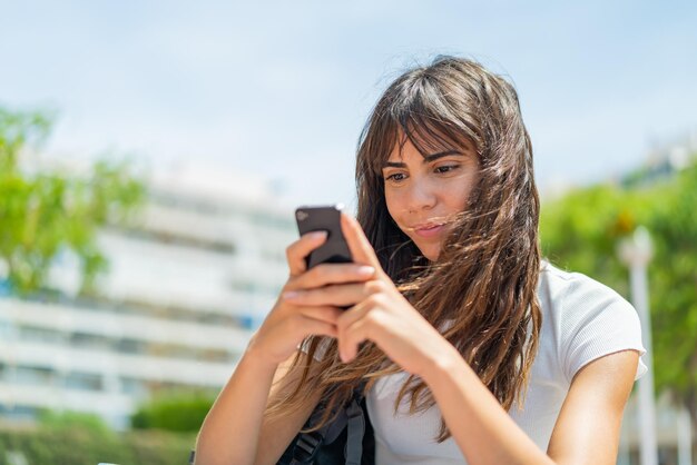 mujer joven, en, aire libre, utilizar, teléfono móvil