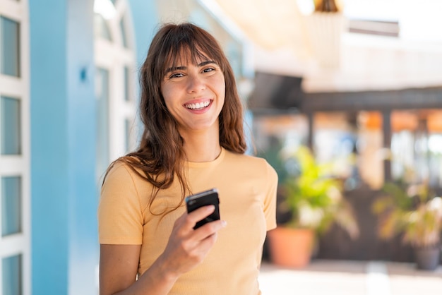 mujer joven, en, aire libre, utilizar, teléfono móvil