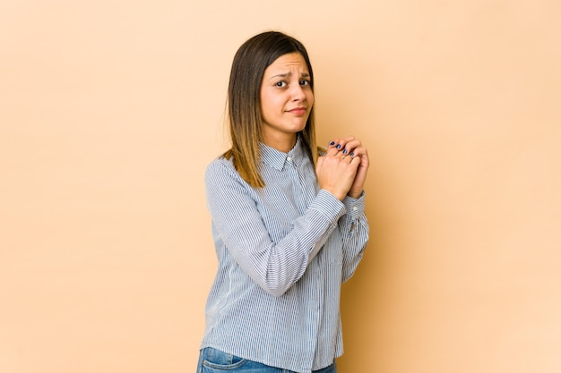 Mujer joven aislada en espacio beige asustada y asustada.