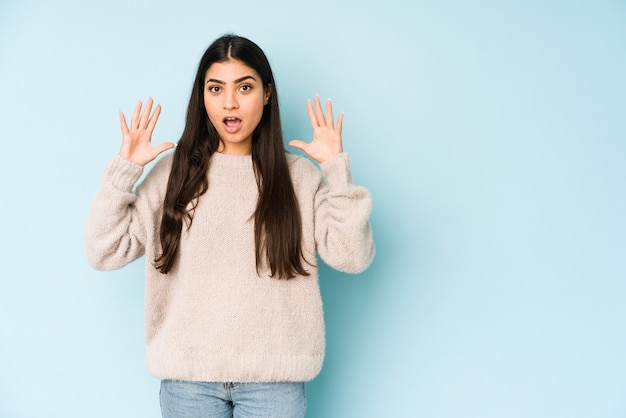 Mujer joven aislada en la pared azul celebrando una victoria