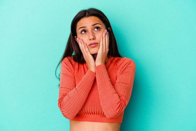 Mujer joven aislada en la pared azul lloriqueando y llorando desconsoladamente