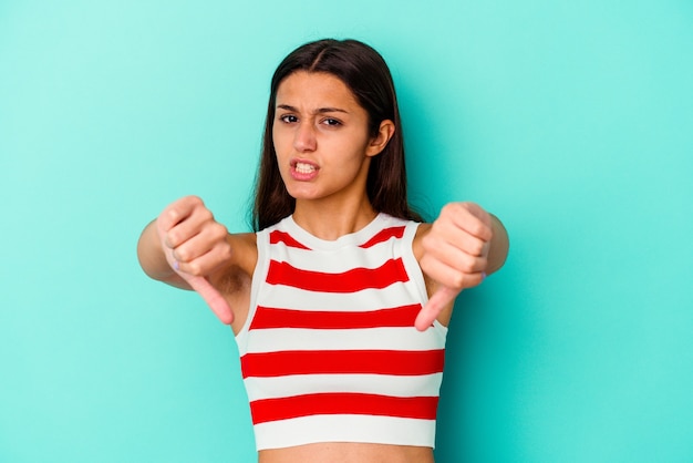 Foto mujer joven aislada en la pared azul mostrando el pulgar hacia abajo y expresando aversión