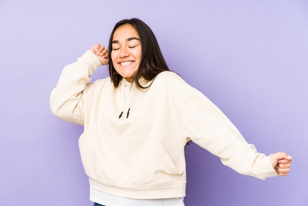 Foto mujer joven aislada en una pared púrpura bailando y divirtiéndose