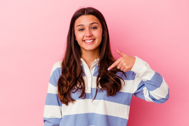 Mujer joven aislada en la pared rosa persona apuntando con la mano a un espacio de copia de camisa, orgulloso y seguro