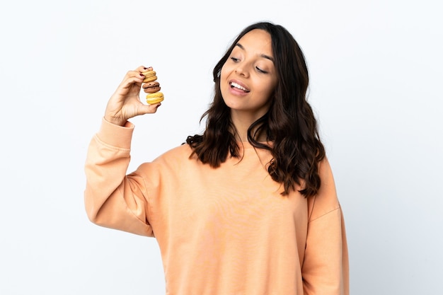 Mujer joven aislado fondo blanco sosteniendo coloridos macarons franceses