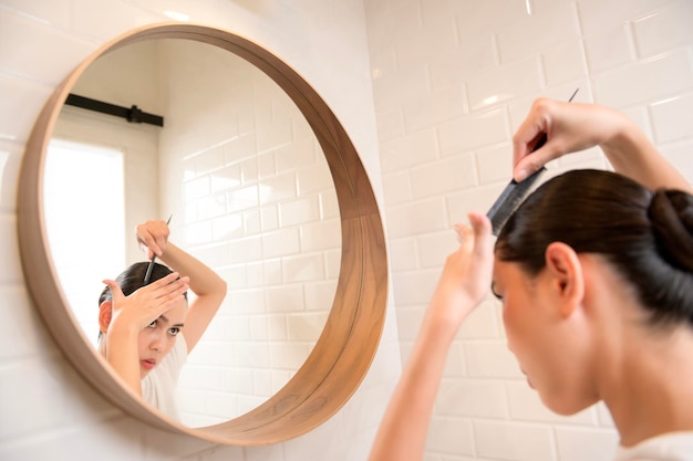 Mujer joven ajustando sus peinados en el baño en casa concepto de bienestar de belleza