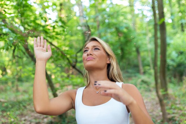 Foto mujer joven al aire libre agita sus brazos mientras es invadida por molestos mosquitos joven turista tratando de deshacerse de los insectos molestos que la acosan en la naturaleza