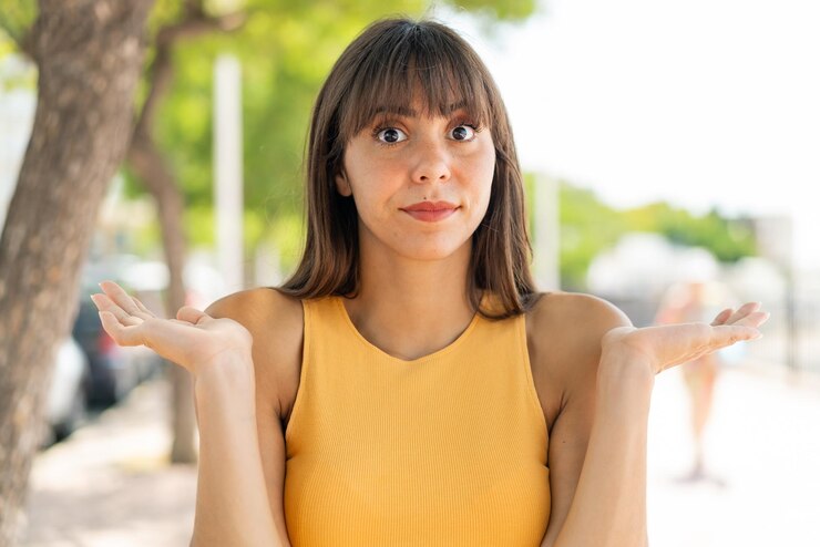 Foto mujer joven al aire libre que tiene dudas mientras levanta las manos