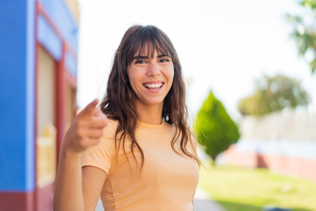 Mujer joven al aire libre sorprendida y apuntando al frente