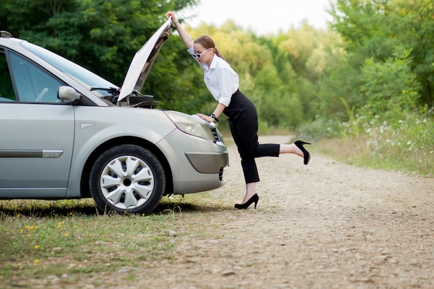 Mujer joven al costado de la carretera después de que su auto se descompuso.