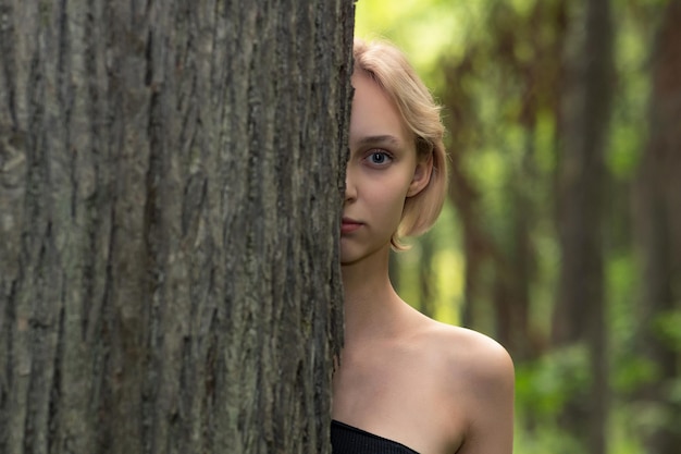 Mujer joven al lado del árbol en el bosque