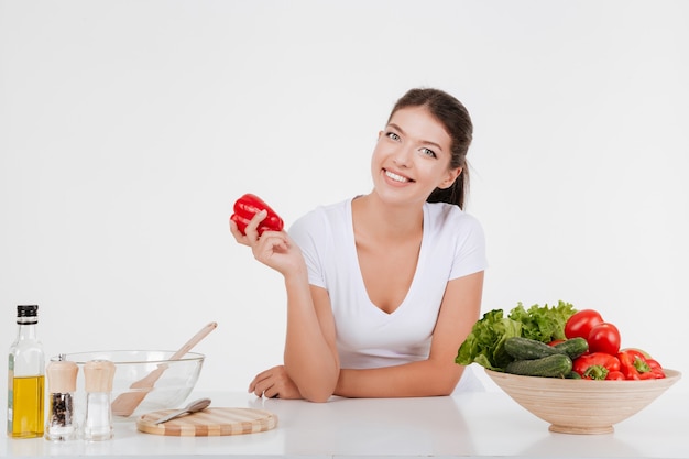 Mujer joven alegre cocinar con verduras y