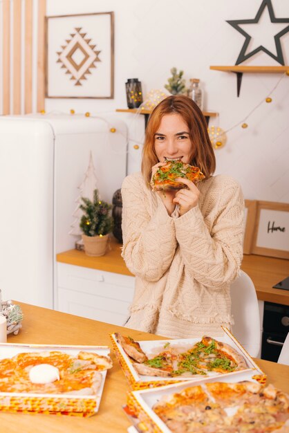 Mujer joven alegre es una rebanada de auténtica pizza italiana y se la come.