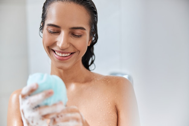 Foto mujer joven alegre con esponja de lufa de baño