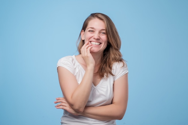 Mujer joven alegre feliz en camiseta blanca riendo en broma divertida.