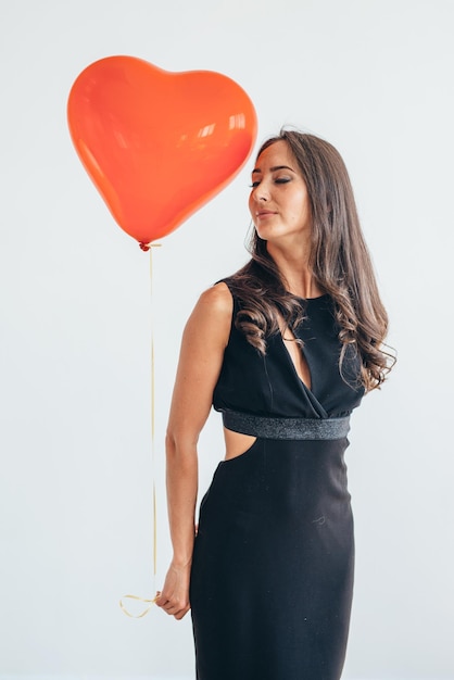 Mujer joven alegre con globos de pie y sonriendo