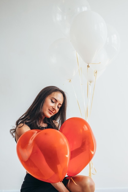 Mujer joven alegre con globos de pie y sonriendo