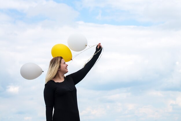 Foto mujer joven alegre con globos en el techo