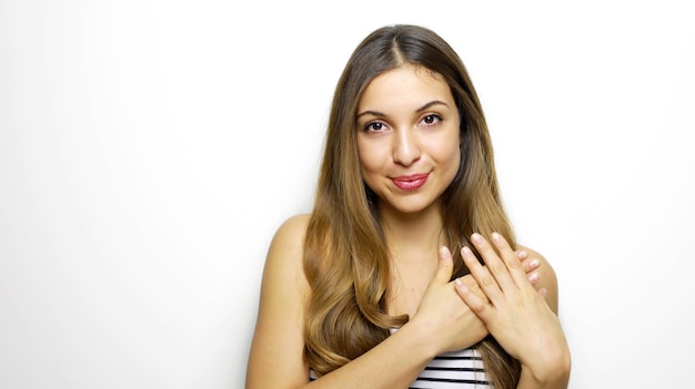 Mujer joven alegre mantiene las manos en el corazón