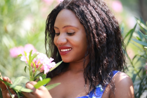 Mujer joven alegre de pie al aire libre con flor.