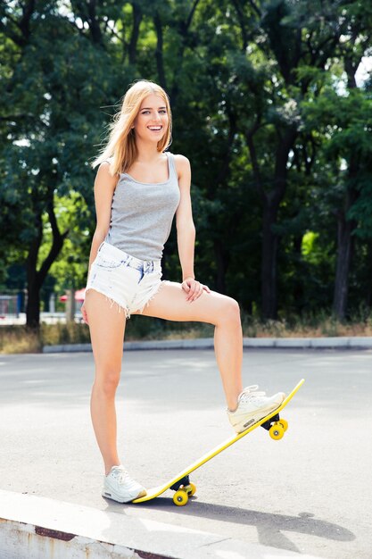 Mujer joven alegre de pie con patineta