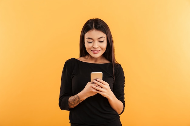 Mujer joven alegre que usa el teléfono móvil.