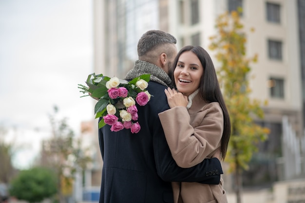 Mujer joven alegre sonriendo mientras sostiene un hermoso ramo de flores