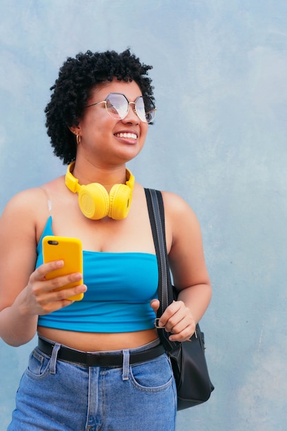 Mujer joven alegre sosteniendo el teléfono al aire libre