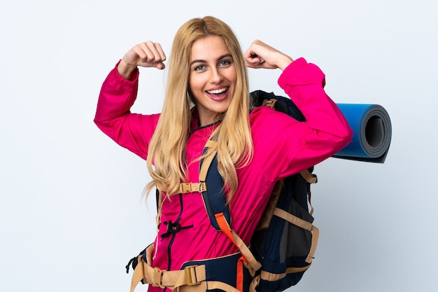 Foto mujer joven alpinista con una gran mochila sobre pared blanca aislada