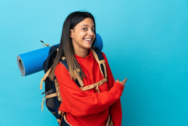 Mujer joven alpinista con mochila apuntando hacia atrás