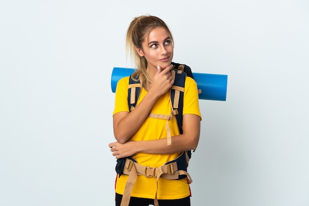 Mujer joven alpinista con una mochila grande posando aislada contra la pared en blanco