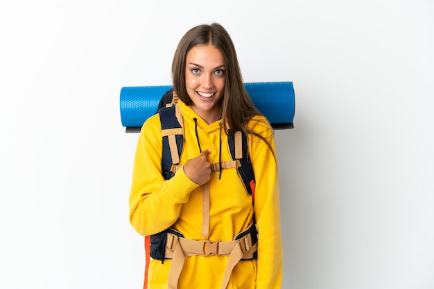 Mujer joven alpinista con una mochila grande sobre fondo blanco aislado con expresión facial sorpresa