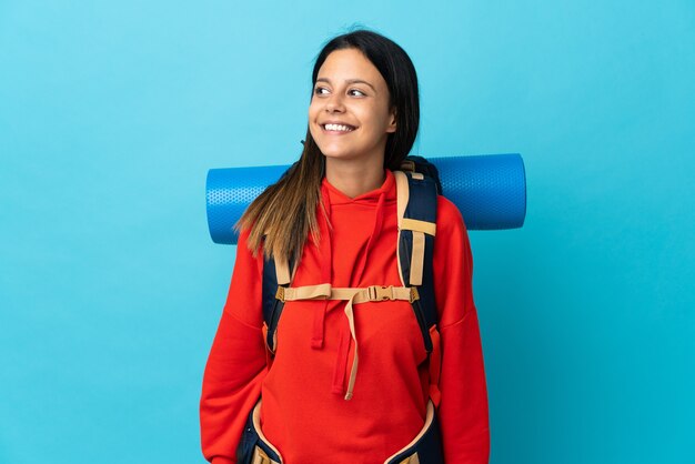 Mujer joven alpinista con mochila mirando hacia el lado y sonriendo