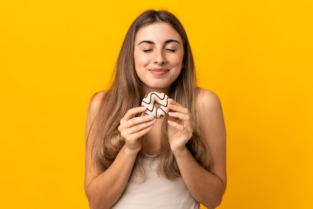 Mujer joven en amarillo aislado sosteniendo una rosquilla