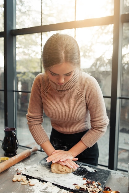 Mujer joven amasa la masa en la cocina