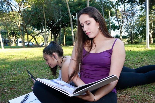 Foto una mujer joven con un amigo leyendo un libro mientras se relaja en un campo de hierba