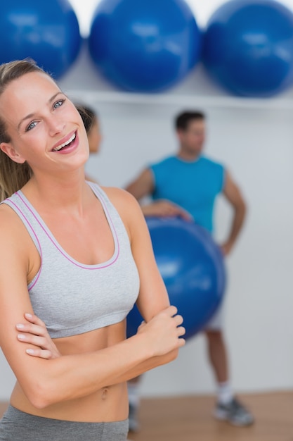 Mujer joven con amigos en segundo plano en el gimnasio