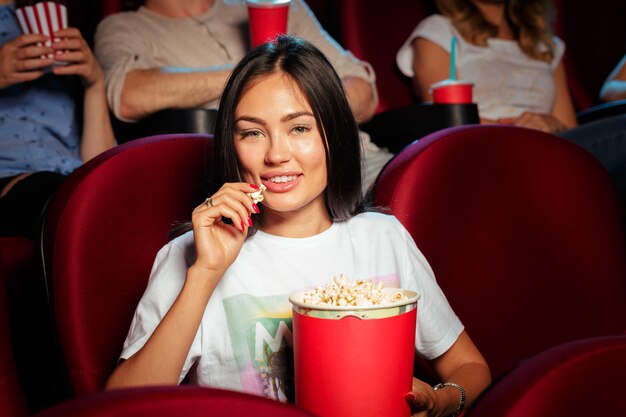 Mujer joven con amigos viendo la película en el cine