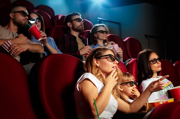 Mujer joven con amigos viendo una película en el cine