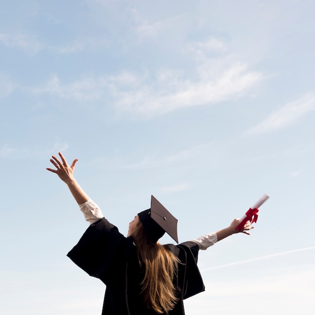 Foto mujer joven de ángulo bajo celebrando su graduación