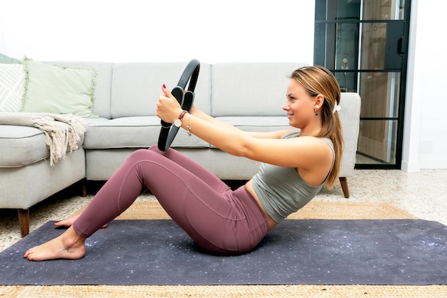 Mujer joven con anillo de pilates en casa