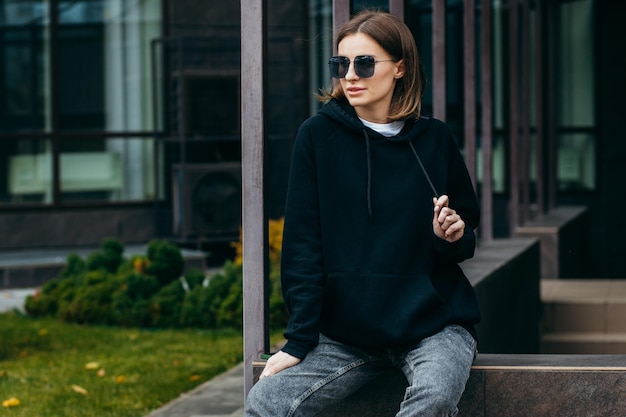 mujer joven, en, anteojos, y, negro, hoodie