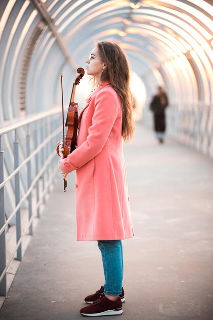 mujer joven, en, anteojos, posición, en, el, aéreo, pasaje, tenencia, un, violín