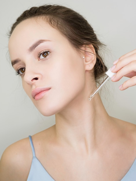 mujer joven aplica aceite cosmético en el cuello