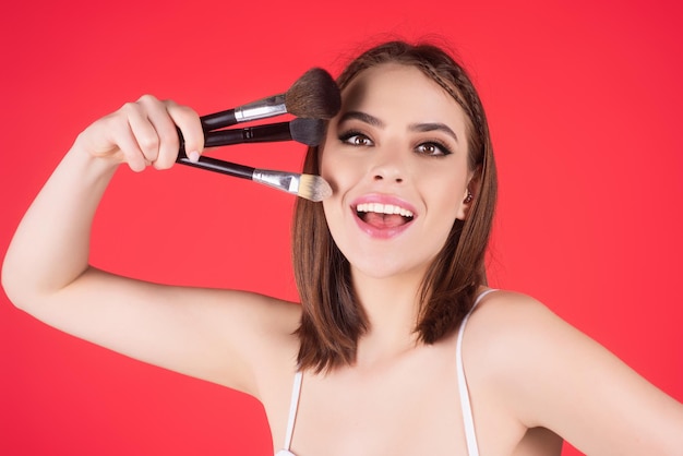 Mujer joven aplica polvo en la cara usando pincel de maquillaje niña hermosa haciendo contorno aplicar blus