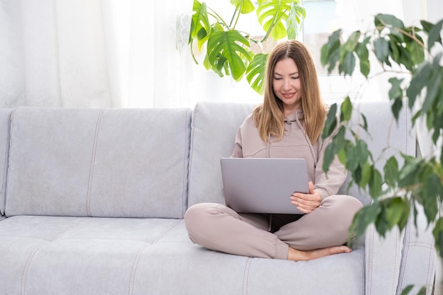 Mujer joven con aplicaciones de búsqueda en línea e learning estudiando navegar por internet en el sofá