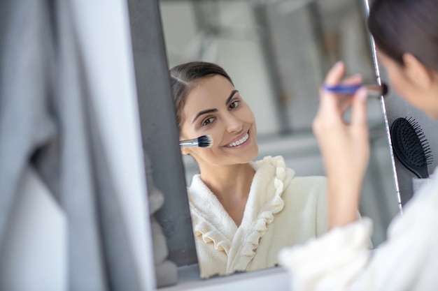 Mujer joven aplicando cosméticos con un cepillo