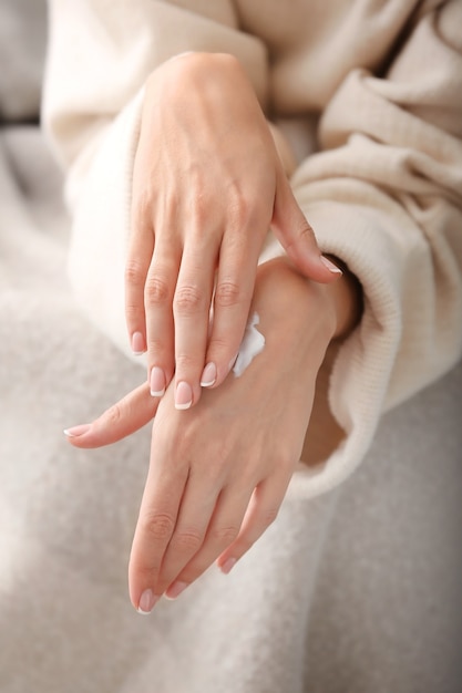 Mujer joven aplicar crema natural sobre la piel en casa, primer plano