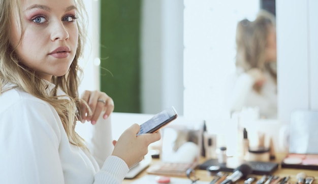 Mujer joven aplicar maquillaje al modelo en el salón