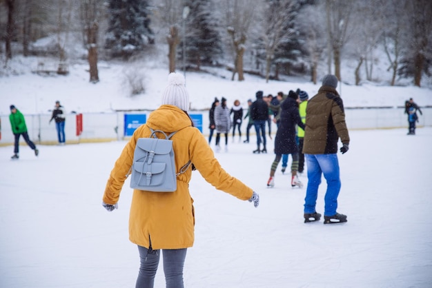 Mujer joven aprender a esquiar en la pista de hielo de la ciudad